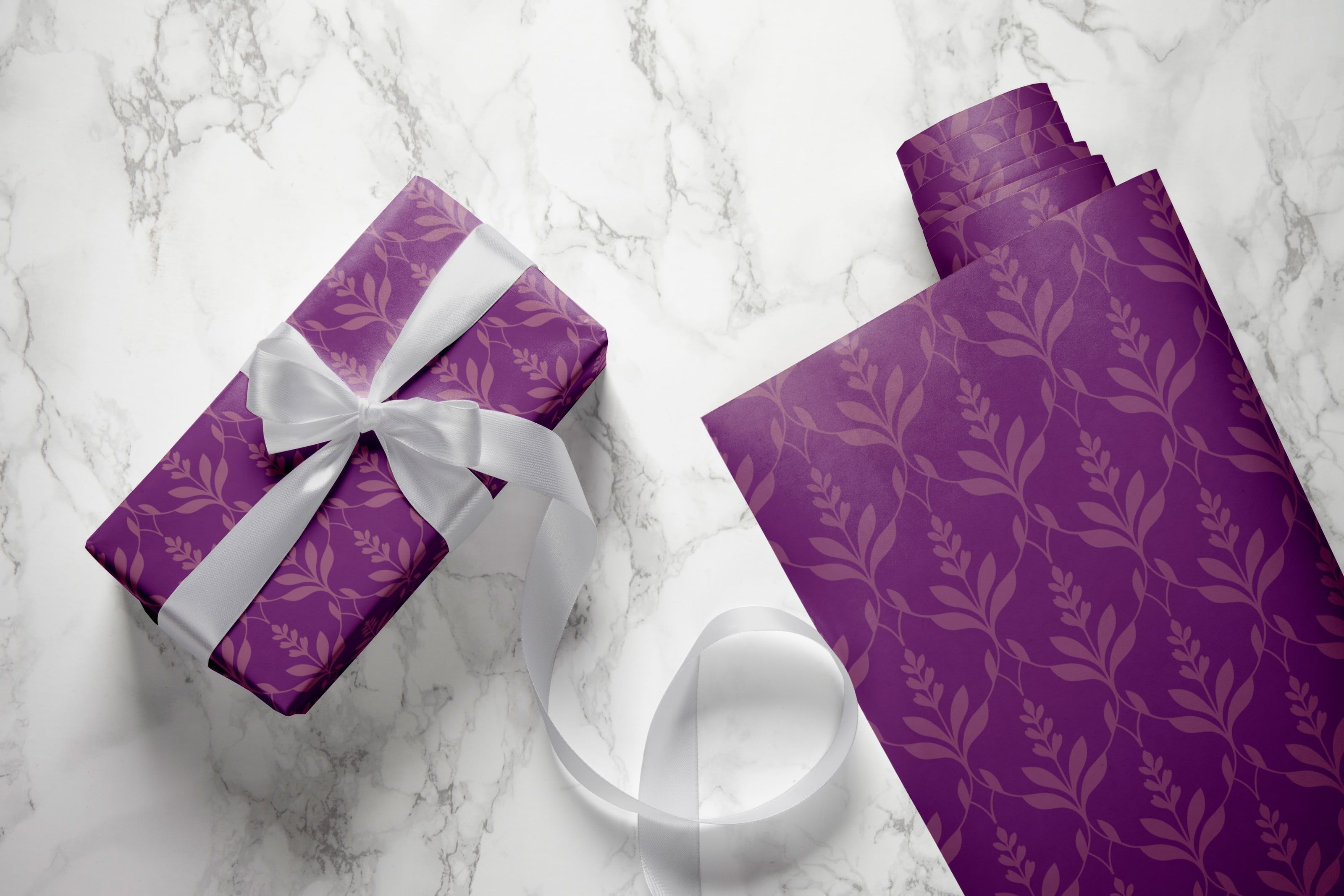 A box wrapped in Zama's purple lattice paper with a white satin ribbon, on marble